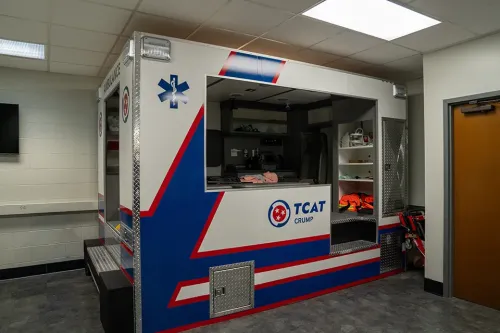 TCAT Crump ambulance simulation box with open side showing stretcher and supplies in training room.